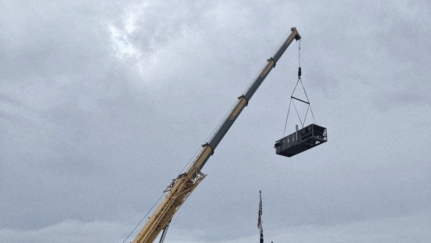 A crane lifts a unit onto a building's roof